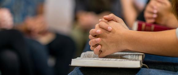 Hands laying on top of a religous text. 