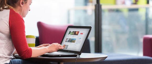 A student sitting at a table using Surreylearn on her laptop