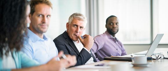  Committee sat at a large meeting table having a discussion. 