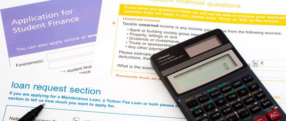 A selection of loan application forms with a calculator laying on top of them