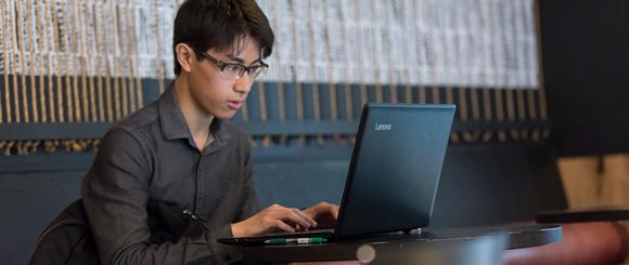 A student sitting at a table using a laptop