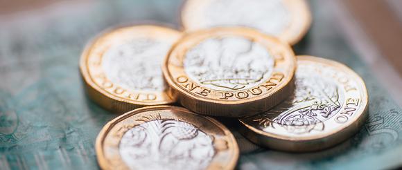 Pound coins sitting on top of a five pound note.