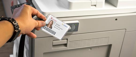 A student swiping her campus card on a printer.