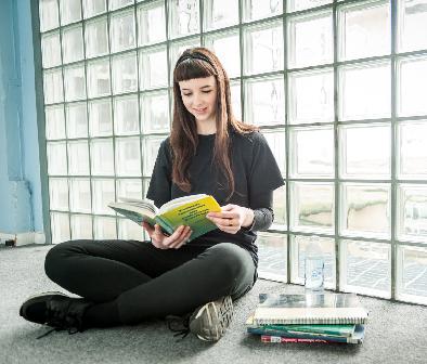 Student sitting in the library reading a book