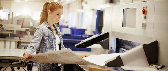 A student taking artwork out of a printing press at a work placement.