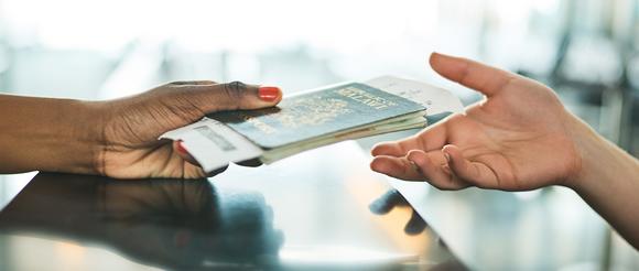 Passport and boarding pass being passed to a member of airline staff.