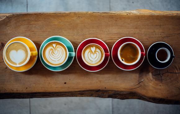 A line of mugs filled with different types of coffee