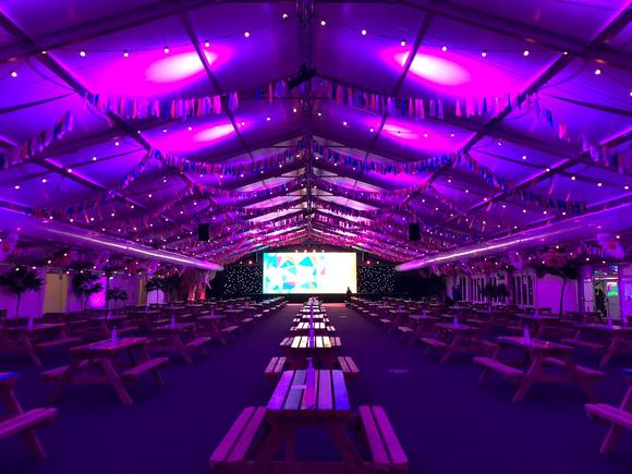 A photo of inside The Marquee showing picnic benches and a big screen