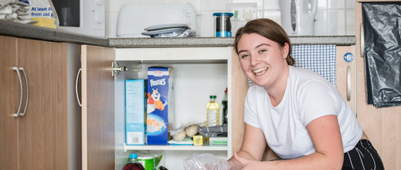 Student kneeling in front of cupboard unpacking items