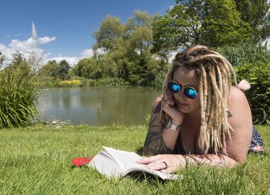 Student reading a book by the lake