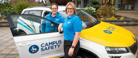 Two Campus Managers stood around the Campus Safety team vehicle